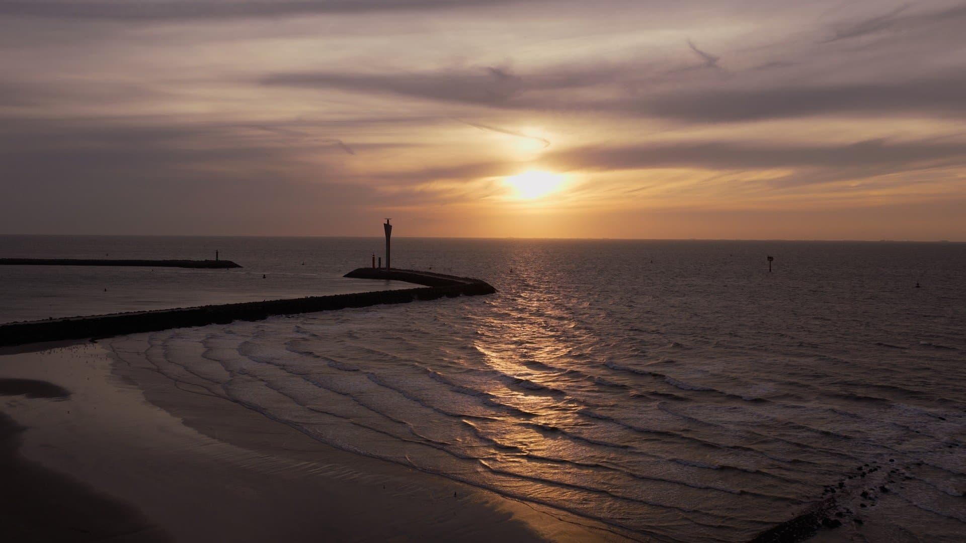 Zonsondergang boven zee aan het staketsel van Oostende
